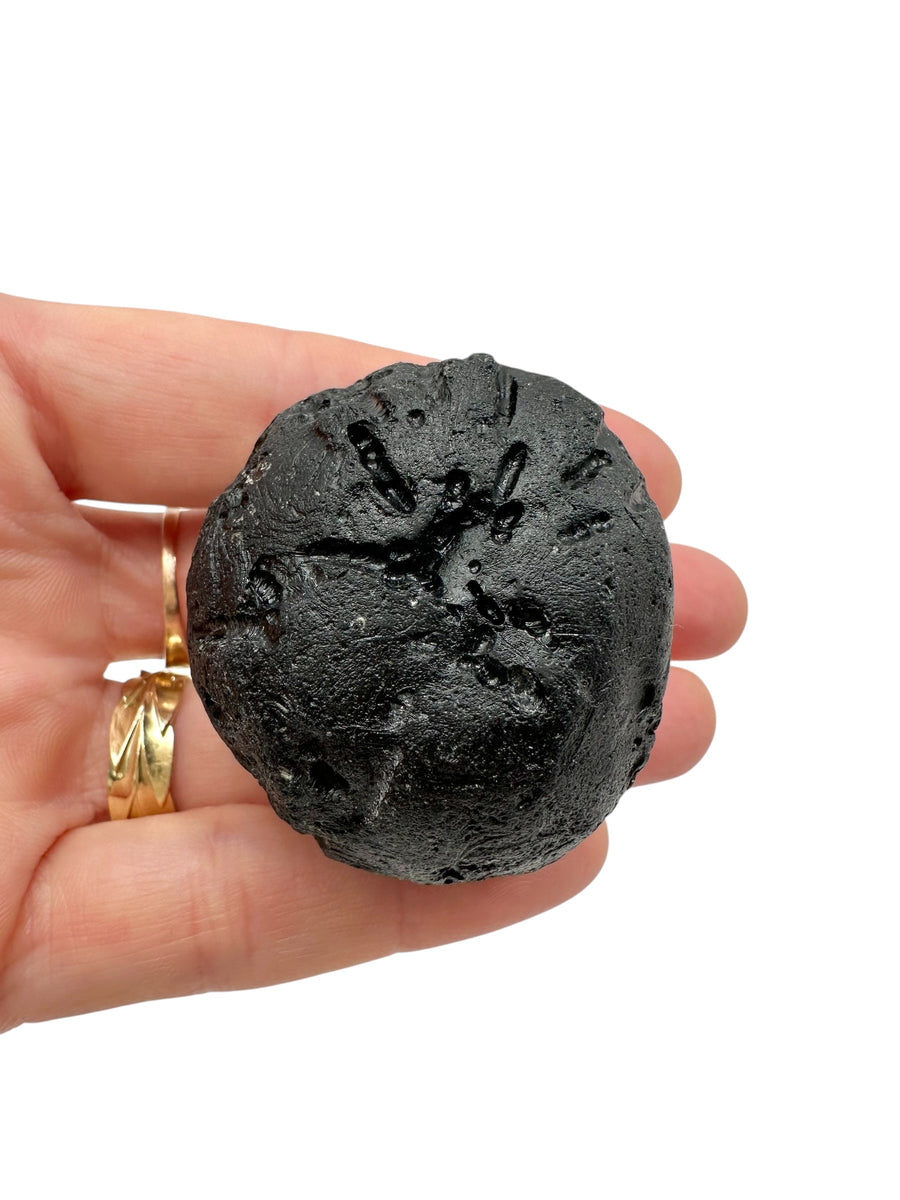 Indochinite grezza nera di forma tondeggiante con solchi profondi di corrosione