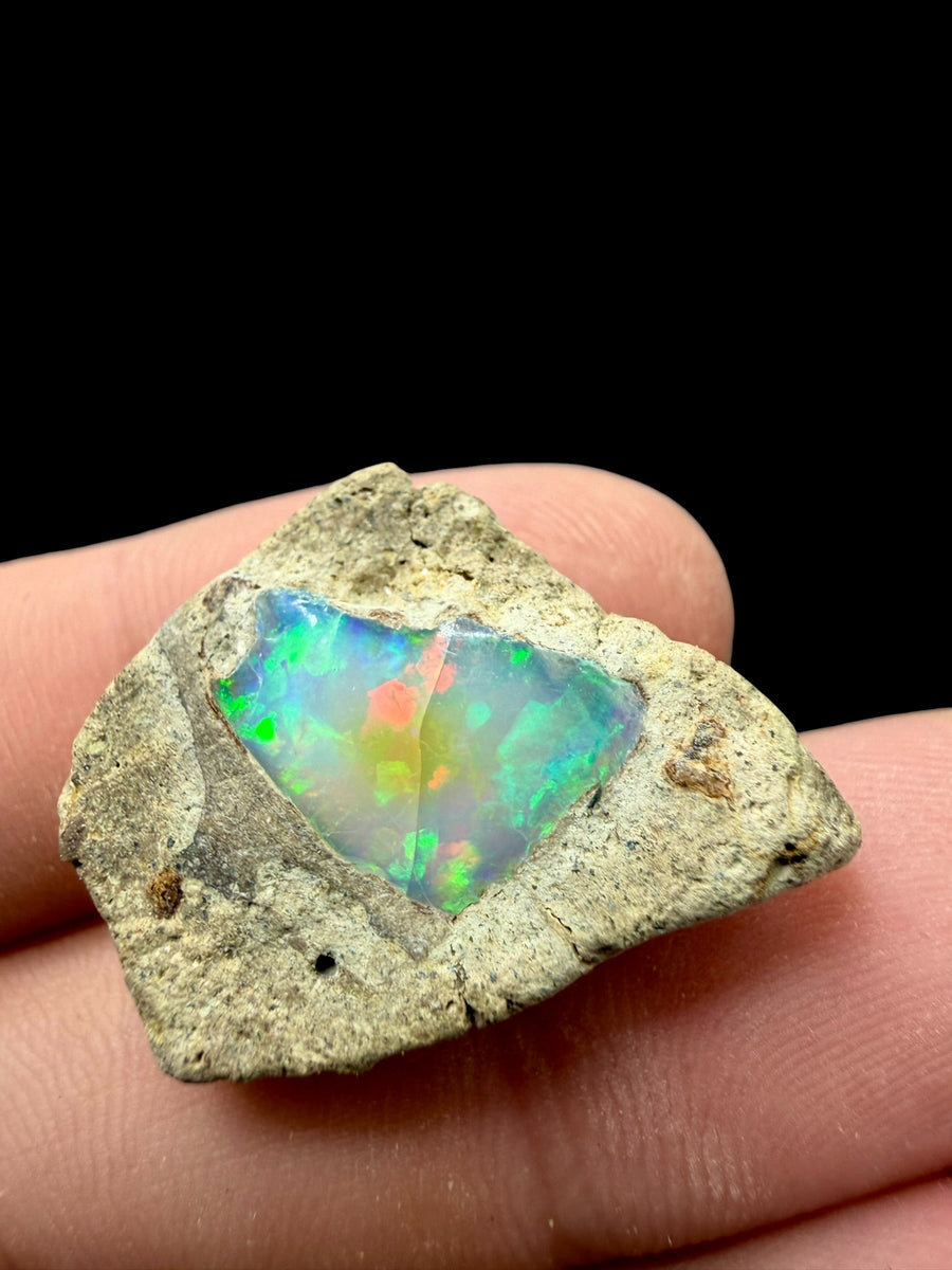 Opale prezioso grezzo del Welo in matrice chiara, con gioco di colore verde, arancio e azzurro