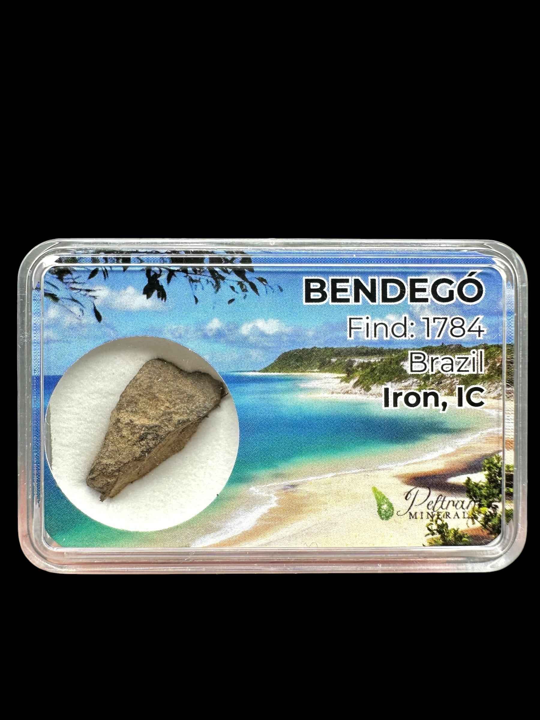 Frammento grezzo di meteorite Bendegó a forma di cuneo, grigio-bruno, in box trasparente con etichetta Brazil Iron IC