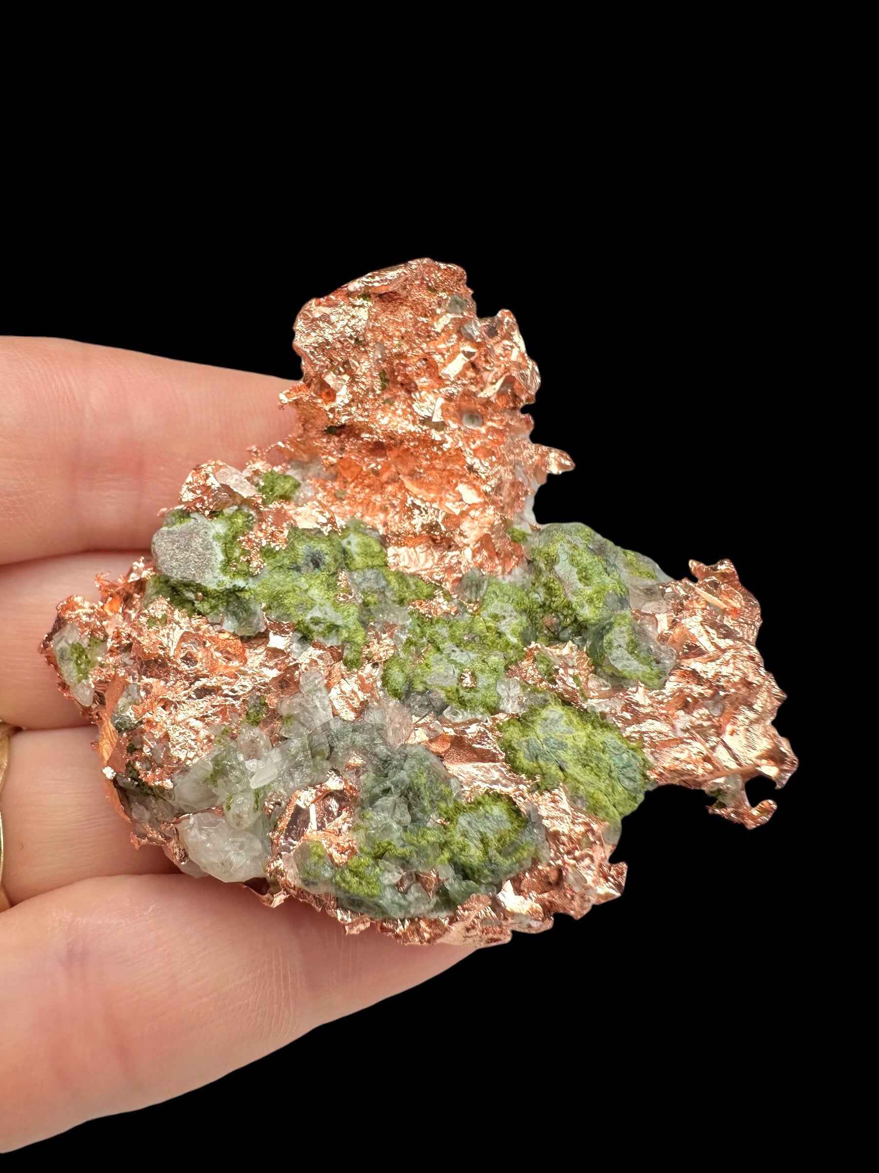 Placca di rame nativo del Michigan con croste verdi di malachite e quarzo bianco, tenuta in mano