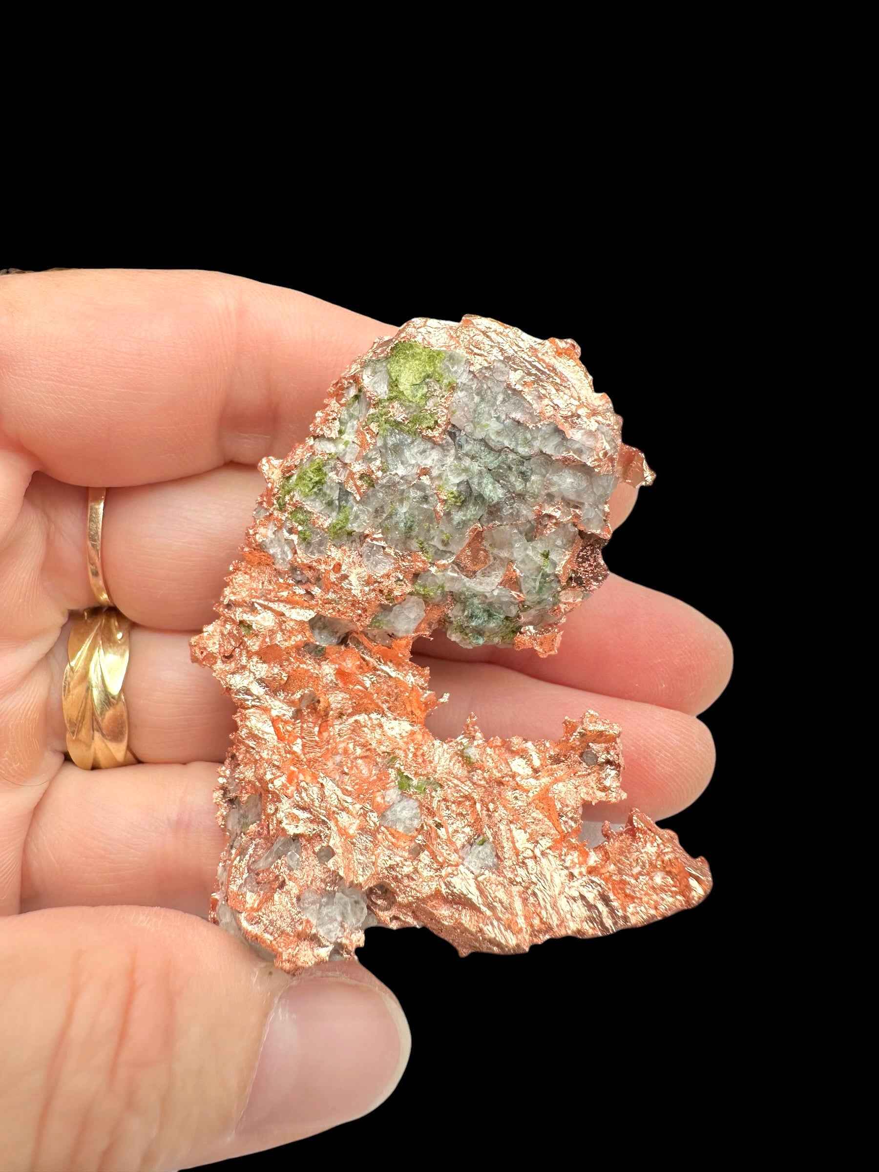 Lamina irregolare di rame nativo del Michigan con macchie verdi di malachite su zona biancastra, tenuta in mano