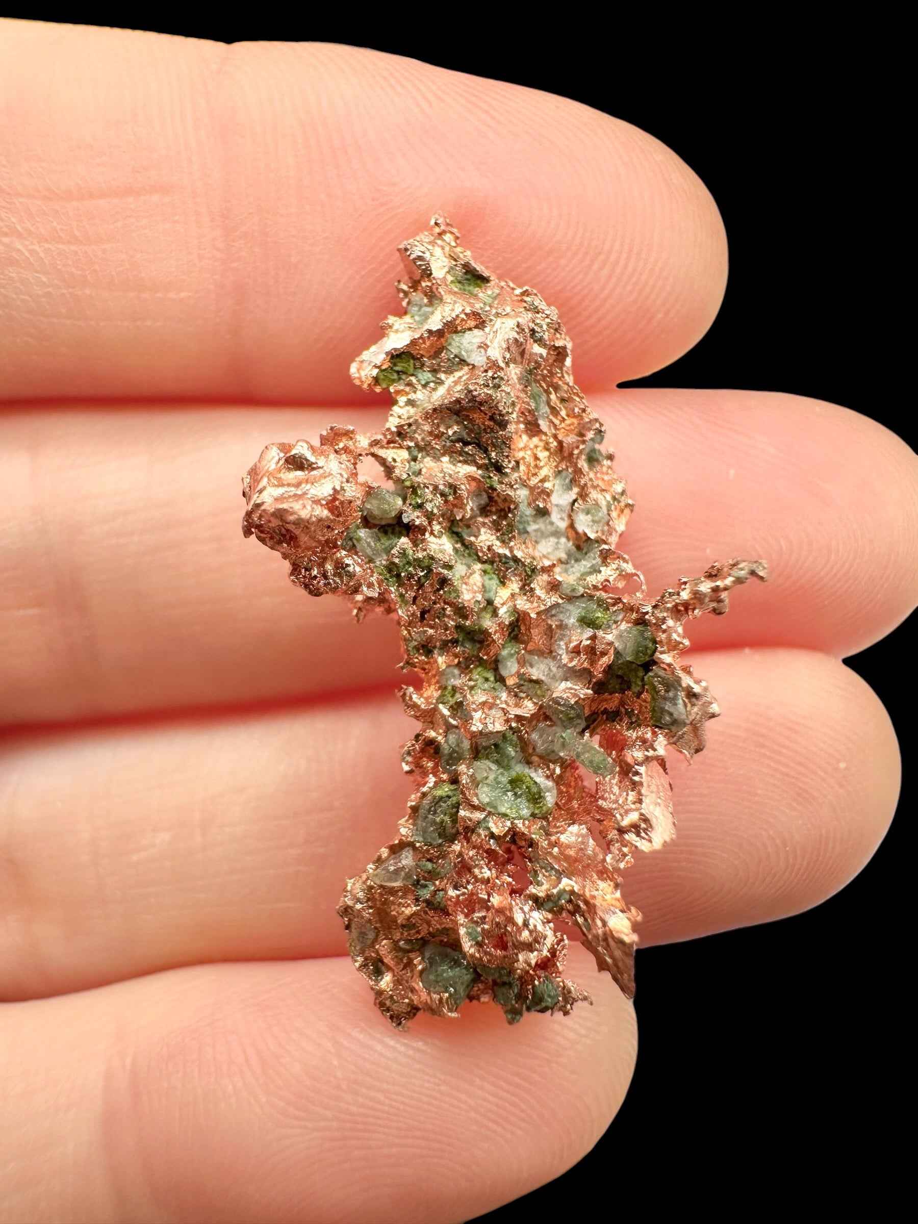 Aggregato ramificato di rame nativo del Michigan con incrostazioni verdi di malachite, tenuto tra le dita