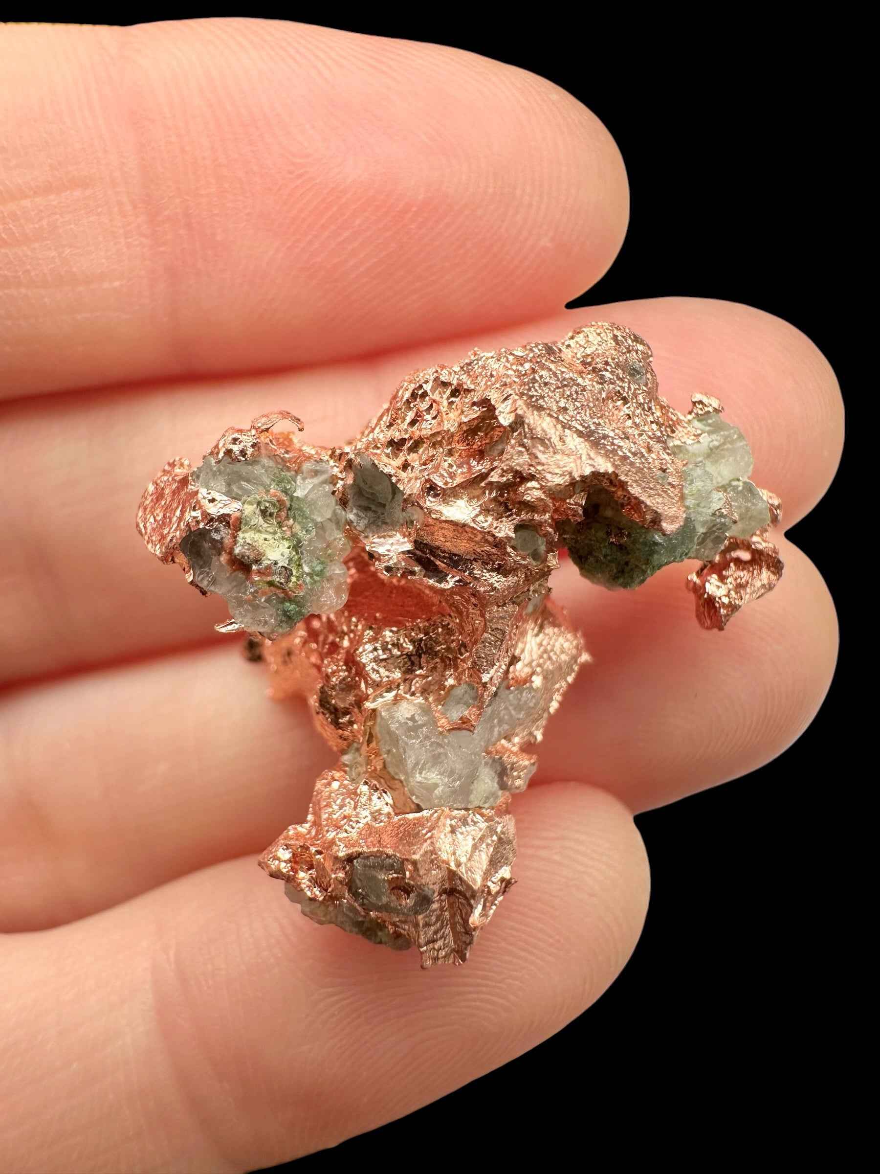Aggregato di rame nativo del Michigan con lamelle lucenti e malachite verde nelle cavità, tenuto fra le dita