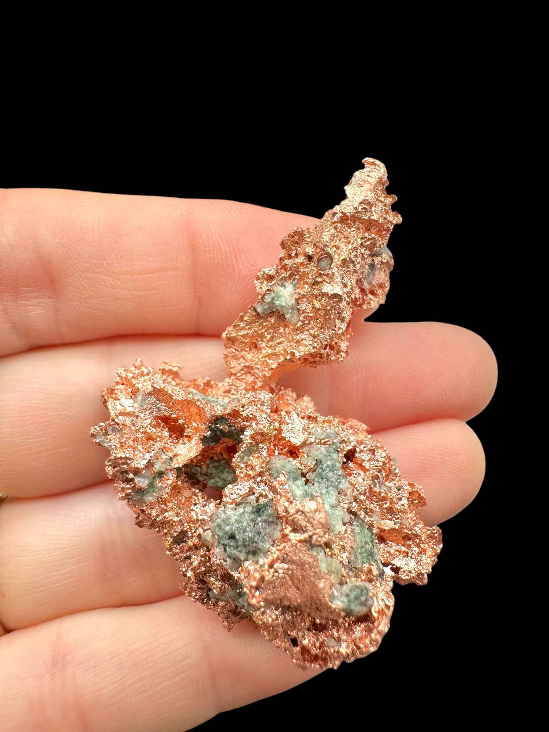 Esemplare di rame nativo del Michigan con malachite verde, tenuto in mano su fondo nero