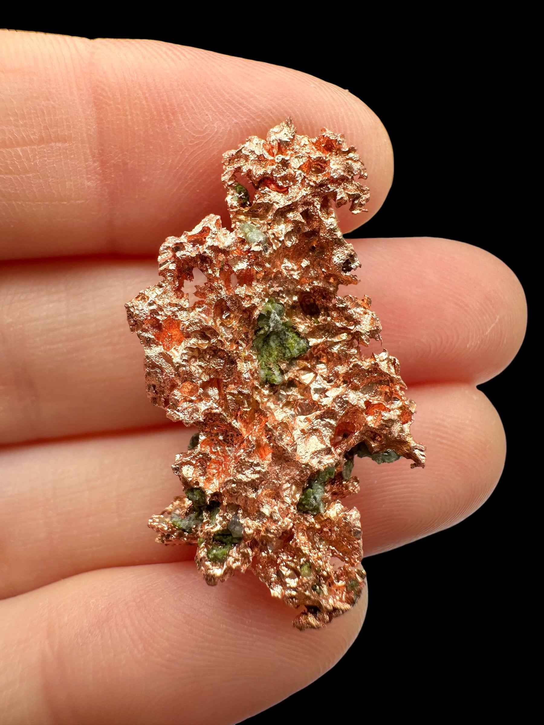 Lamina di rame nativo ramificato del Michigan con macchie verdi di malachite, tenuta tra le dita