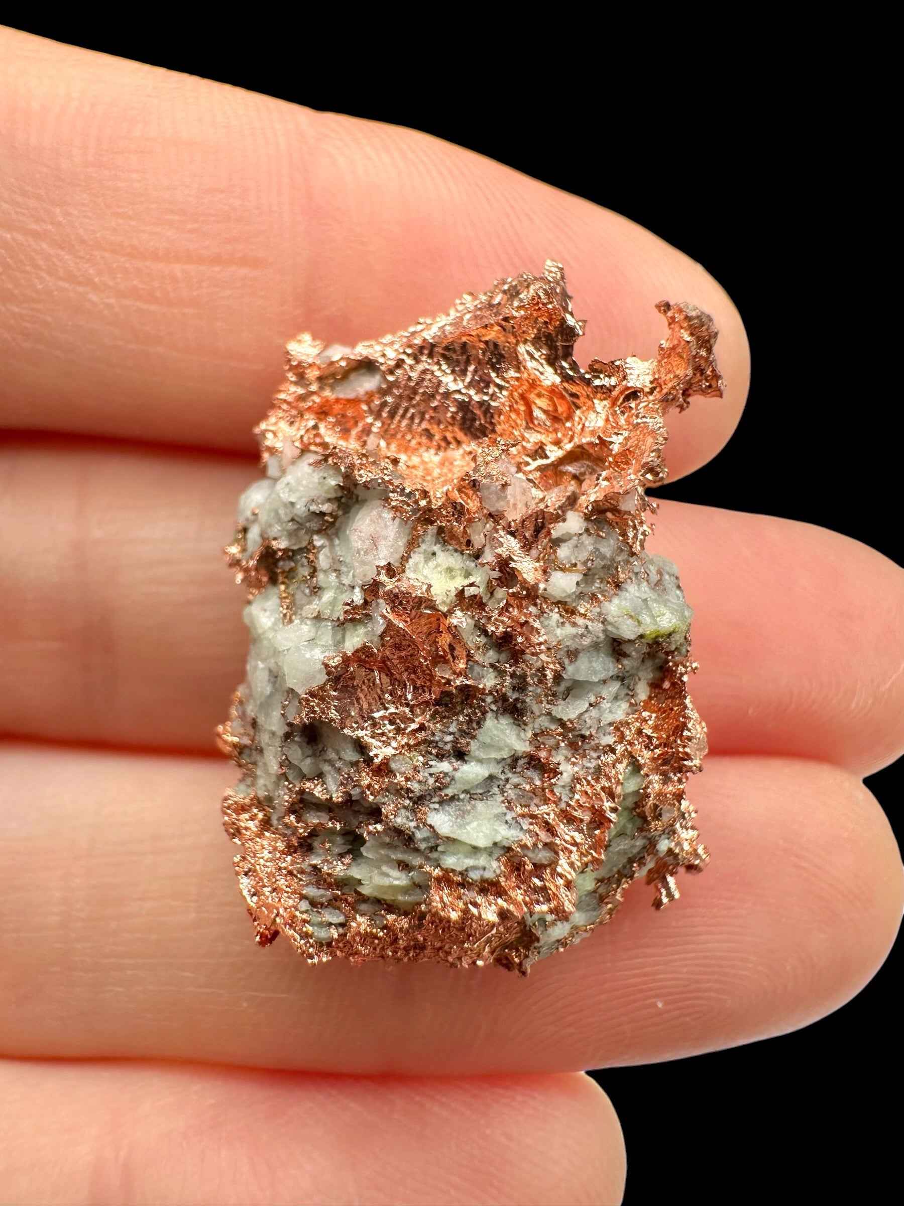 Campione di rame nativo con malachite verde su matrice bianca, Michigan, USA, tenuto tra le dita
