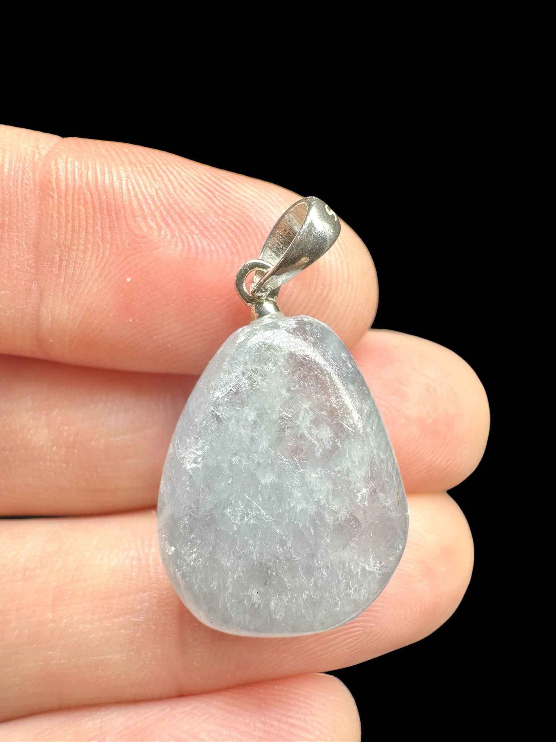 Pendente in celestite azzurra a goccia levigata con cappuccio in argento, tenuto tra le dita