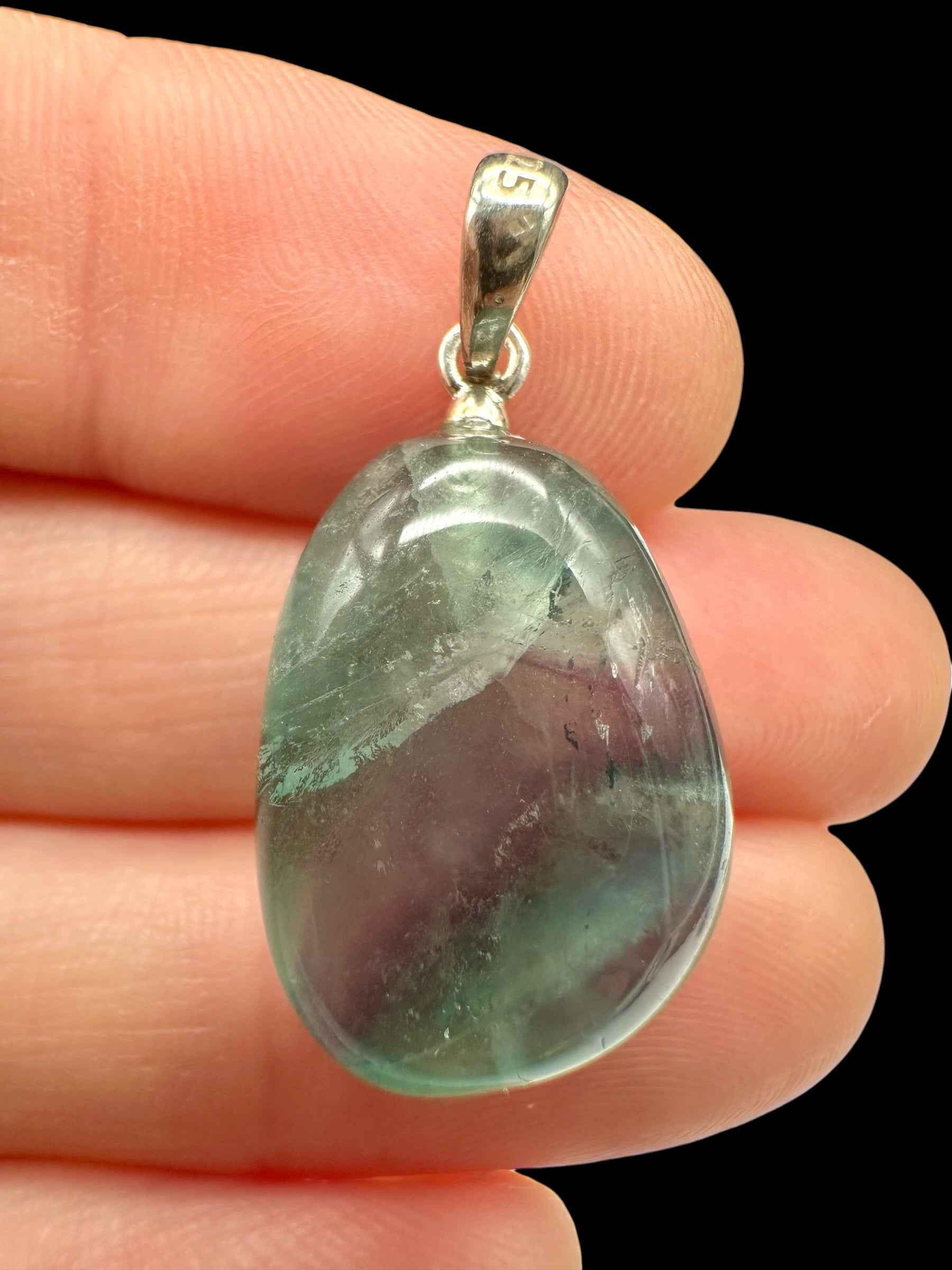 Pendente in fluorite verde e viola levigata a goccia con bordo e appiccagnolo in argento, tenuto tra le dita