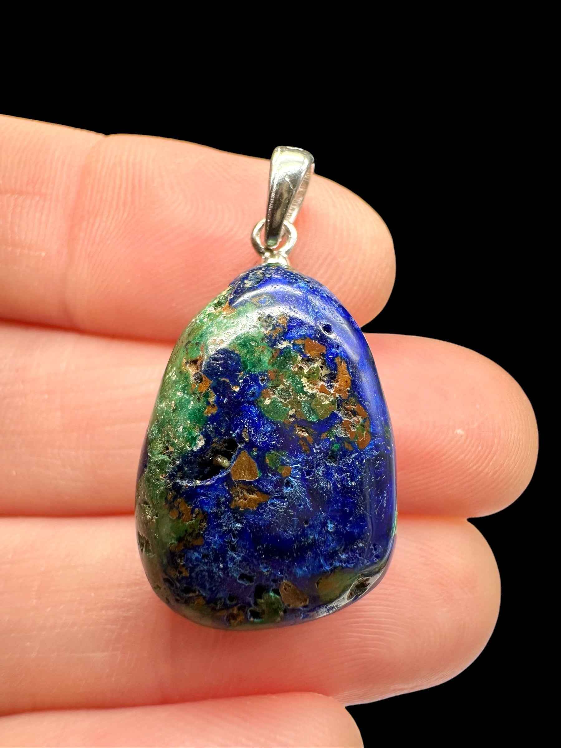 Pendente in azurite blu con malachite verde e matrice ocra, montatura in argento, tenuto tra le dita
