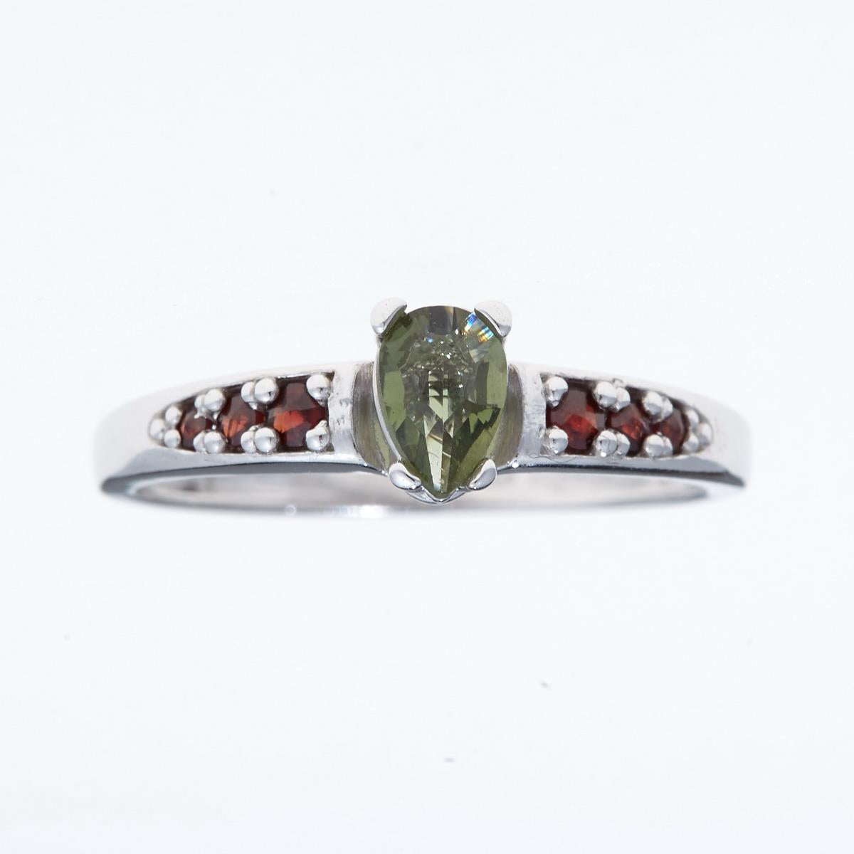 Anello in argento rodiato con moldavite verde a goccia al centro e file di granati rossi sui lati