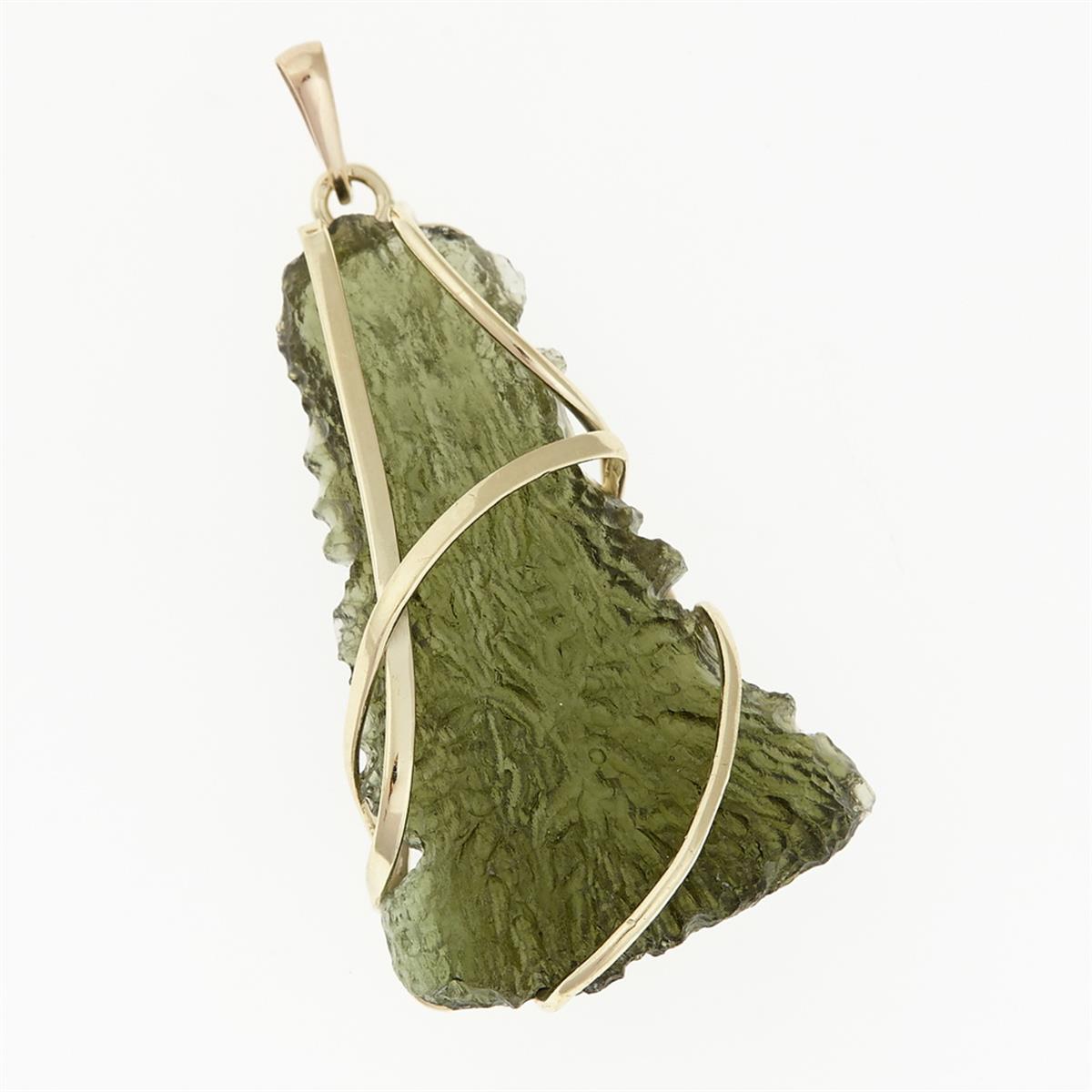 Pendente in moldavite grezza verde oliva di forma triangolare, montatura in oro giallo con nastri curvi incrociati