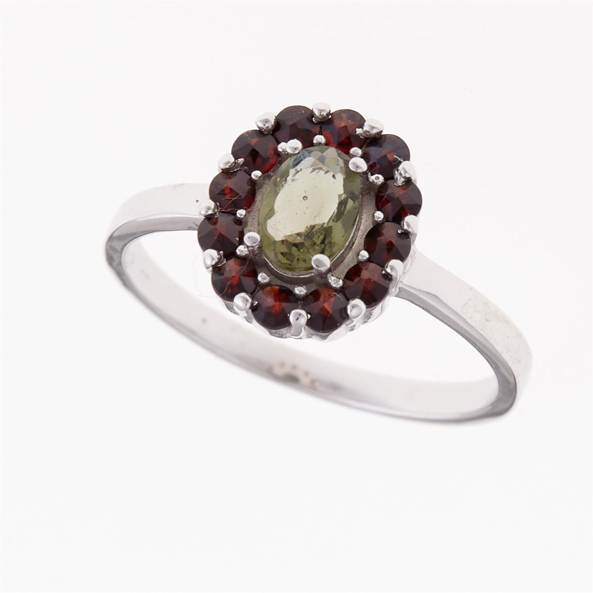 Anello in argento rodiato con moldavite ovale faccettata verde circondata da granati rossi tondi