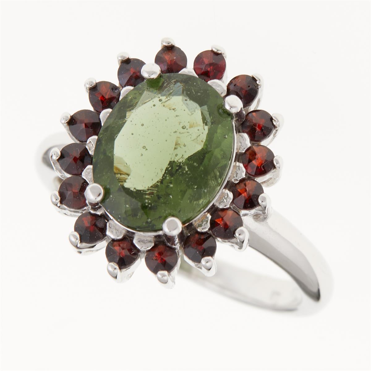 Anello in argento rodiato con moldavite ovale faccettata verde circondata da granati rossi tondi